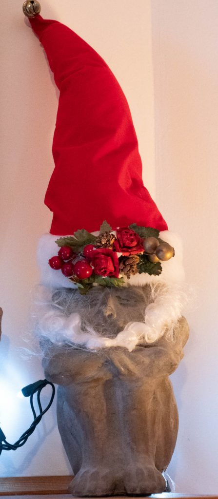 A small stone gargoyle with a "Santa Hat"